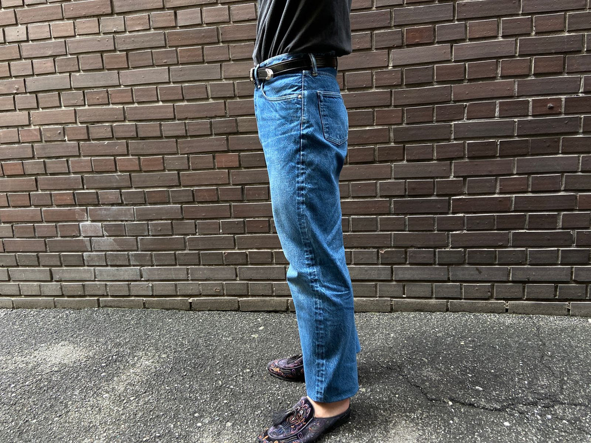 ウォッシュデニムを穿いた立ち姿を真横から見たところ。ウエストの位置から裾までのシルエットが分かる