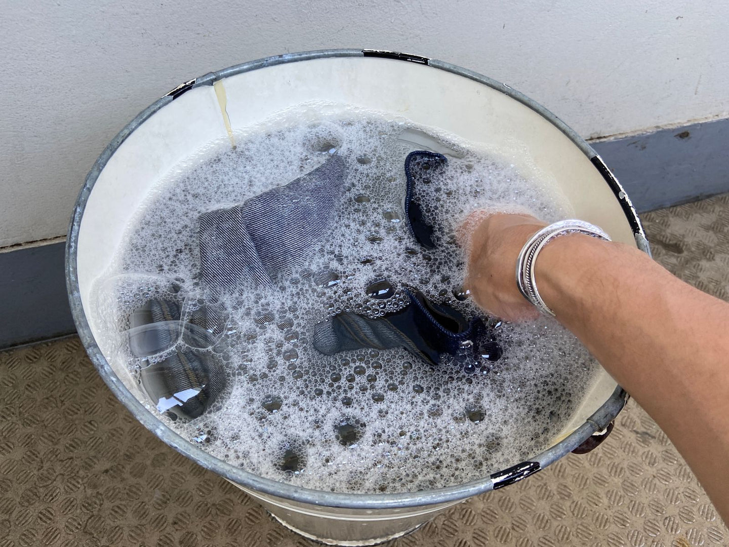 バケツに張った洗剤液の中で、裏返したデニムを手でもみ洗いしているところ